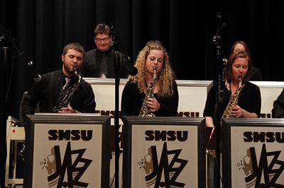 Part of the saxophone section playing during a concert.